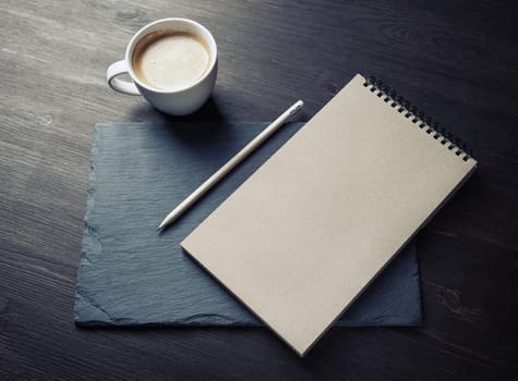 Photo of blank kraft notebook, pencil and coffee cup. Mockup for ID.
