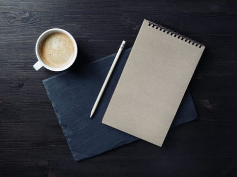 Photo of blank kraft notepad, pencil and coffee cup. Branding mock up. Top view. Flat lay.