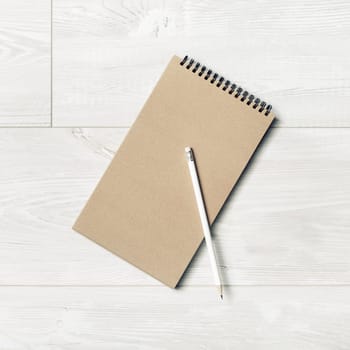 Photo of blank kraft sketchbook and pencil on light wooden background. Top view. Flat lay.