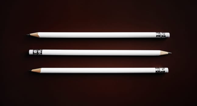 Three simple blank pencils on dark background. Top view. Flat lay.