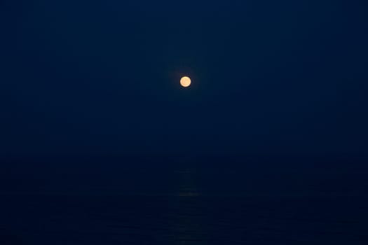 Full Red Moon Glows Brightly in the Blue Sky on a Evening Over the Sea.