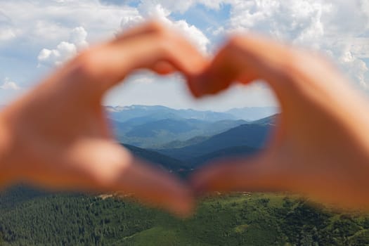 The Couple Make a Heart With Their Hands on the Background of the Sky.