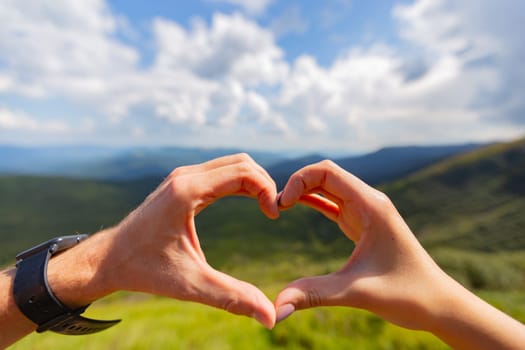 The Couple Make a Heart With Their Hands on the Background of the Sky.