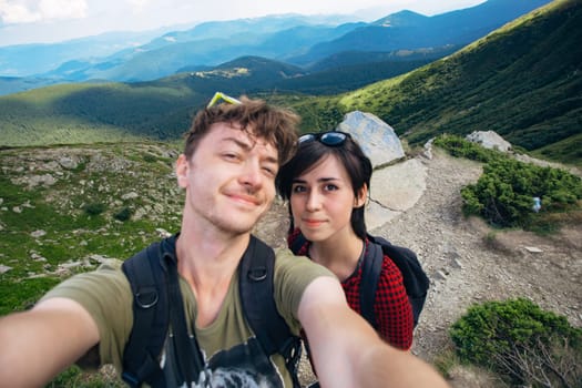 Aerial view of the Great Green Ridge. Guy and Girl Standing on a Big Hill against the Backdrop of a Huge Mountain Landscape.