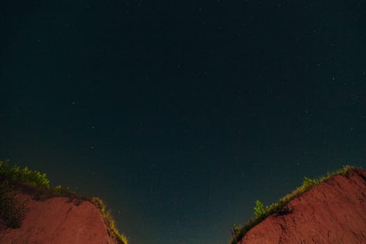 Night Dark Sky with Lots of Bright White Stars and Constellation over the Two Mountain Peaks.