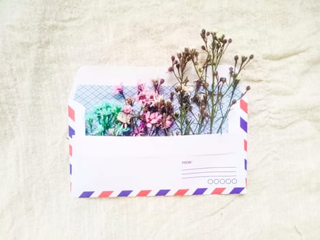 A vintage envelope with small little cute flowers. Gift box greeting card for Valentines on white linen background