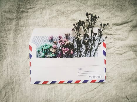 A vintage envelope with small little cute flowers. Gift box greeting card for Valentines on white linen background