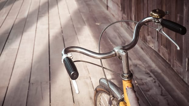 Bicycle handle bar close up. Vintage filter wooden floor background. Good old day concept holiday idea