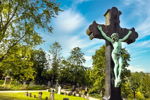Jesus on the cross on a cemetery with blue sky in the summer