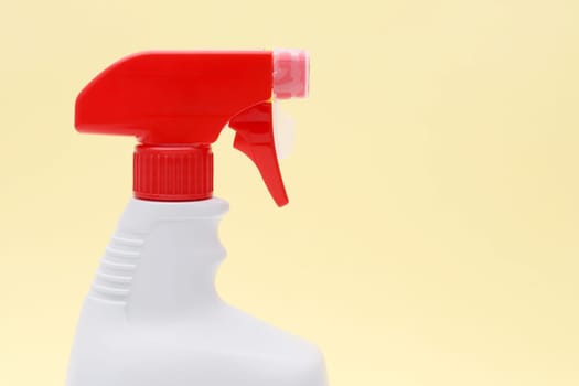 close up of white plastic bottle with spray and foam nozzle on yellow background