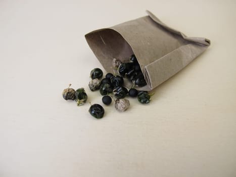 Asparagus seeds, fruits and black seed pods on a wooden board