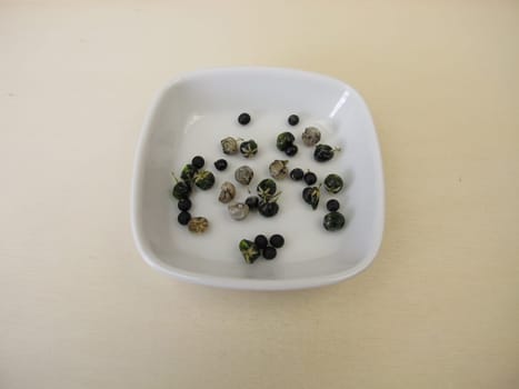 Asparagus seeds, fruits and black seed pods on a wooden board