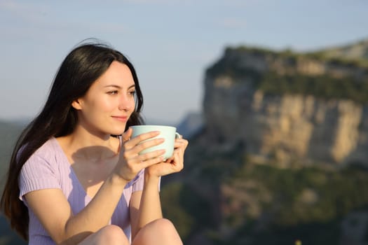 Asian woman looking away drinking coffee in the mountain
