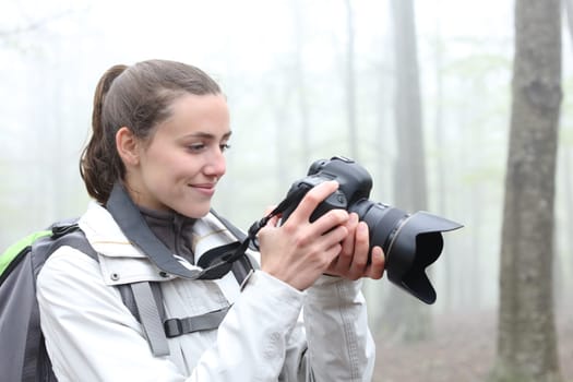Hiker checking photos on dslr camera in a forest