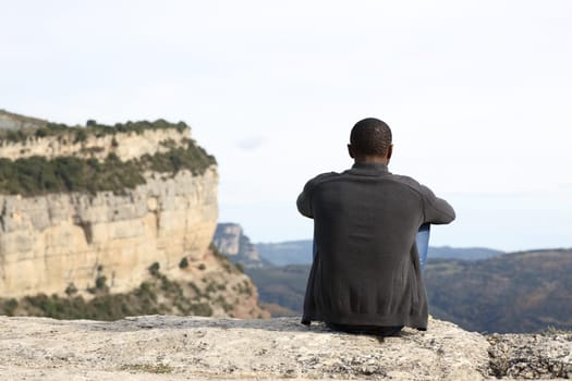 Man with black skin sitting in nature contemplating