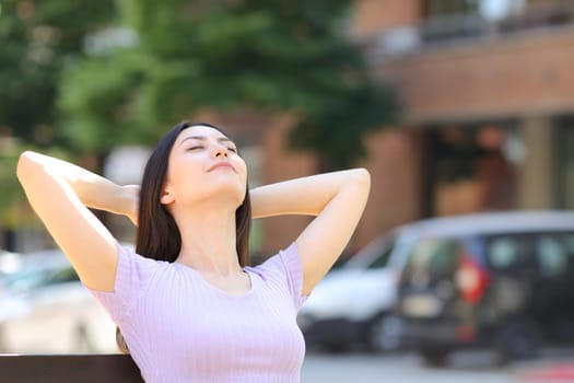 Relaxed asian woman sitting on bench in the street