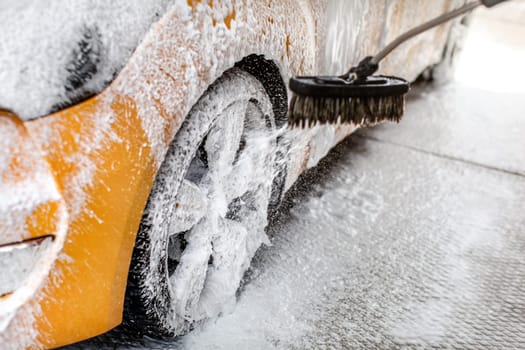 Foam spraying to yellow car wheel, when washed in carwash.