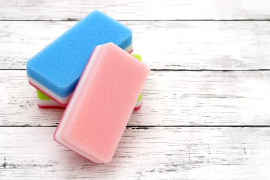 color rectangular sponges for washing dishes and cleaning on white wooden background