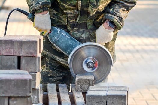 A worker with a circular saw cuts paving slabs in close-up. High quality photo