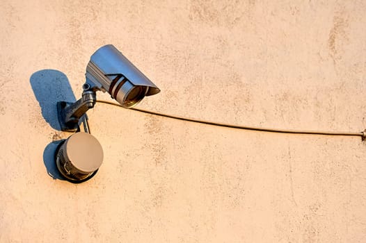 A surveillance camera is hanging on the wall of the house. High quality photo