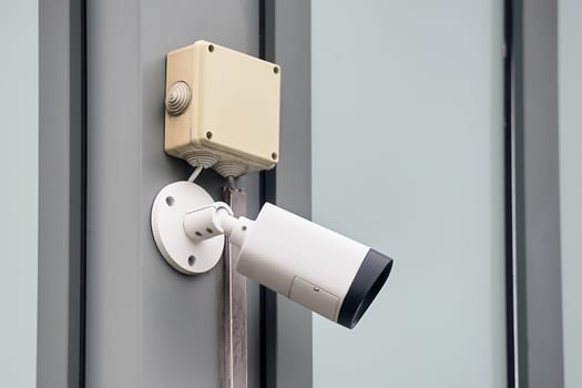 A video surveillance camera hangs on a metal profile. High quality photo