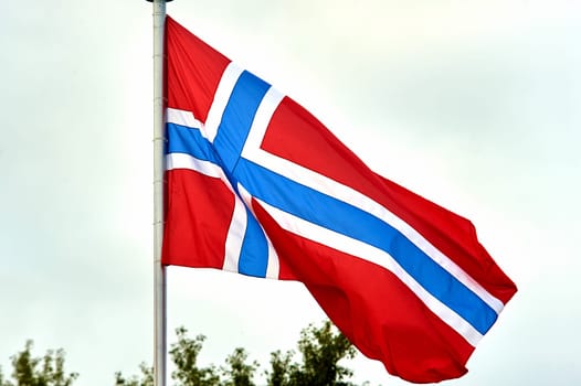 The flag of Norway hangs on the flagpole. High quality photo