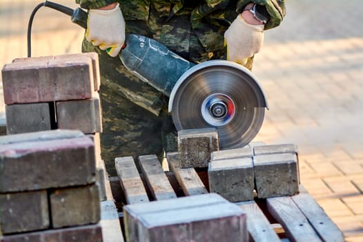 A worker with a circular saw cuts paving slabs in close-up. High quality photo