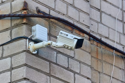 A surveillance camera is hanging on a brick wall. High quality photo