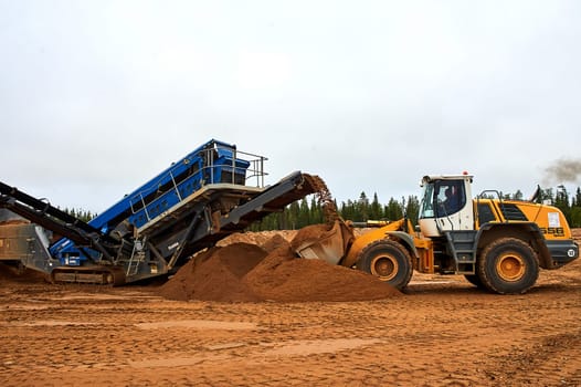 The front loader in the quarry collects a bucket of sand. High quality photo