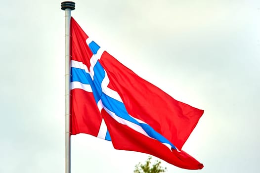 The flag of Norway hangs on the flagpole. High quality photo