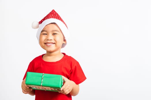 Asian little child cute boy smile and excited, Kid dressed in red Santa Claus hat hold gift box on hands concept of holiday Christmas Xmas day or Happy new year isolated on white background