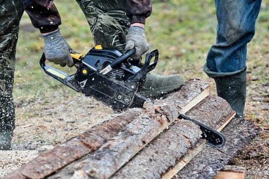 a chainsaw is used to cut wood outdoors. High quality photo