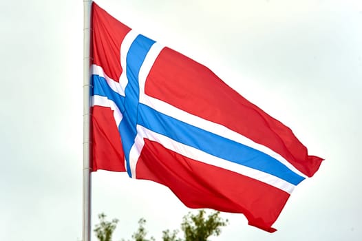 The flag of Norway hangs on the flagpole. High quality photo