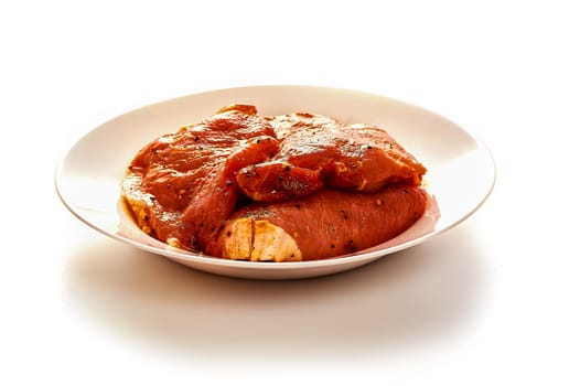 Pork in marinade lies on a white plate on a white isolated background. High quality photo