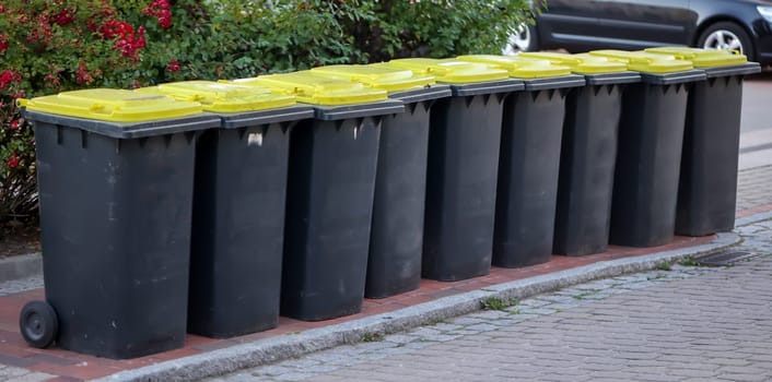 Several tons, yellow bins for plastic waste on a street.