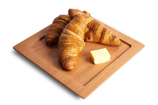 Two breakfast croissants on a wood board with butter