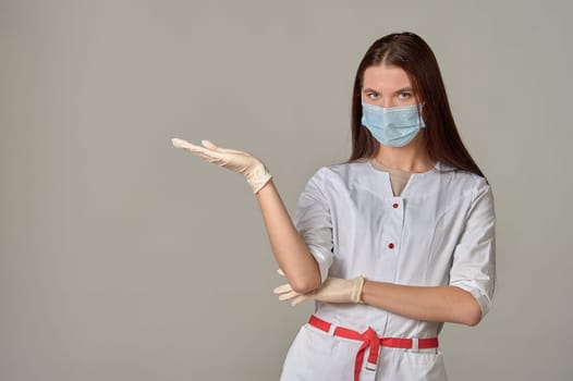 A female doctor in a medical mask points to an empty place, copy space. High quality photo