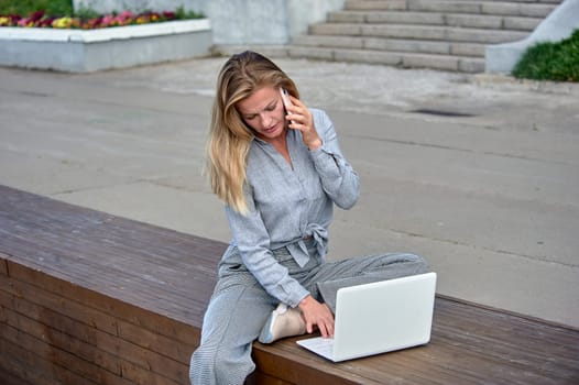 A woman with a laptop sits on a wooden platform, works online. High quality photo