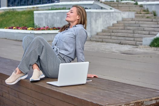 Woman with laptop sitting on a bench and resting. High quality photo