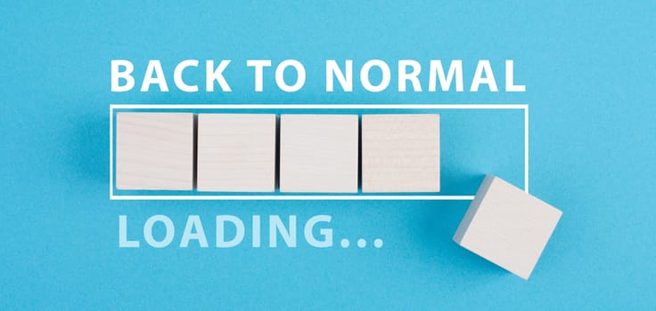 Back to normal is standing on a blue background, loading bar with wooden cubes, life after covid-19