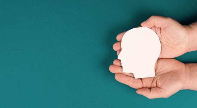 Holding a paper cut out head in the palms, symbolic for brainstorming, having an idea, new concepts, copy space for text