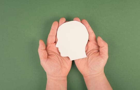 Holding a paper cut out head in the palms, symbolic for brainstorming, having an idea, new concepts, copy space for text