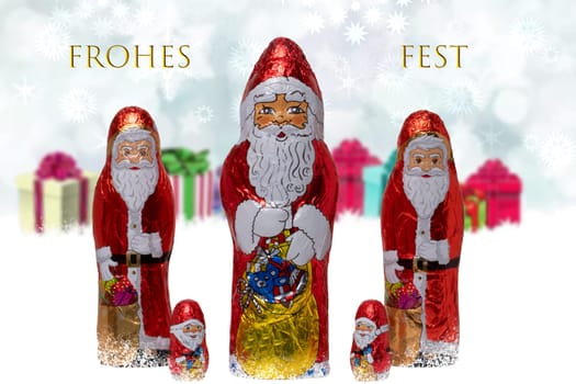 Christmas greeting card. Closeup of various cheerful wrapped chocolate Santa Claus over festive abstract blurred gift boxes. Merry christmas text in german. Macro.