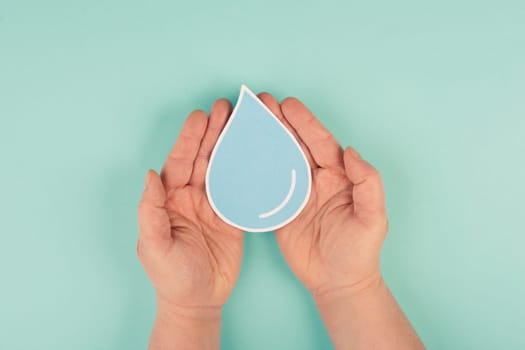 Hands holding a drop of water, paper cut out, environmental issue, copy space for text