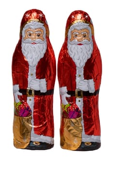 Chocolate Santa isolated. Close-up of two cheerful wrapped chocolate Santa Claus or the good Saint Nicolas figurine isolated on a white background. Macro photograph.