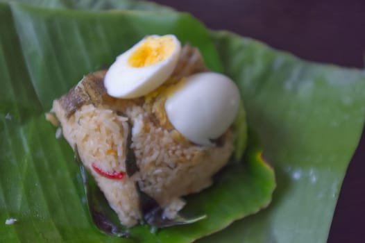 Crispy Gourami Fish and herb fried rice with boil egg on banana leaf