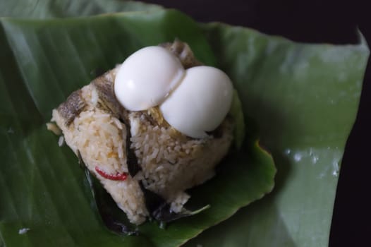 Crispy Gourami Fish and herb fried rice with boil egg on banana leaf