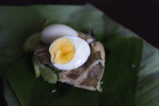 Crispy Gourami Fish and herb fried rice with boil egg on banana leaf