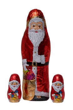 Chocolate Santa isolated. Close-up of three cheerful wrapped chocolate Santa Claus or the good Saint Nicolas figurine isolated on a white background. Macro photograph.