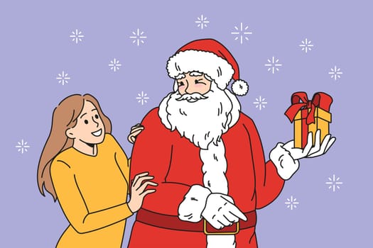 Preparation for Christmas holidays concept. Positive young woman standing and hugging Santa holding present present in box with ribbon vector illustration